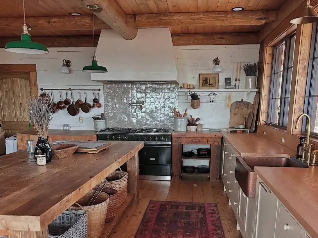 Rustic farmhouse kitchen design ideas with reclaimed wood counters, a black range, copper pots, apron sink, and vintage rug